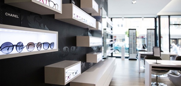 Modernes Optikergeschäft mit beleuchteten Brillenregalen und eleganter Inneneinrichtung.